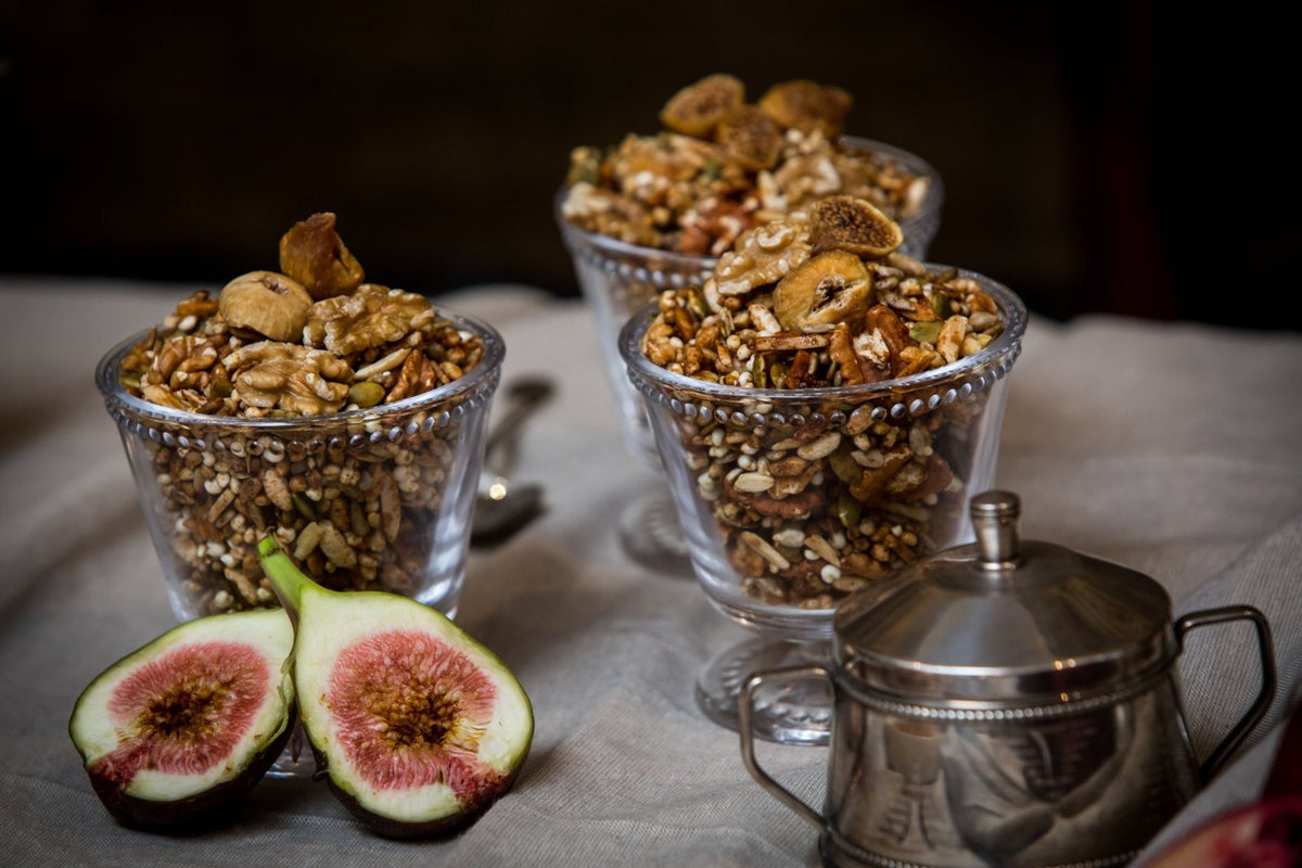 Glasses of Fig, Walnut and Cinnamon granola with fresh cut figs and a silver sugar pot